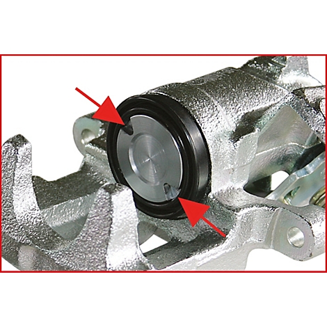 Nahaufnahme eines Bremssattels mit zwei roten Pfeilen, die auf das Innere des Bremssattels zeigen.